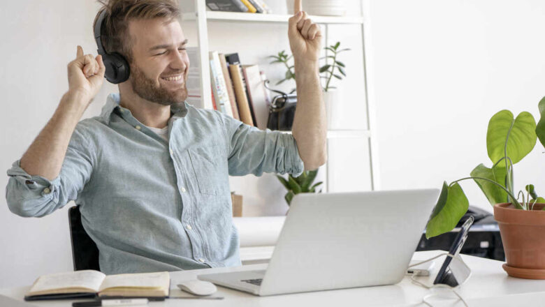 Excited man listening to music at desk in office